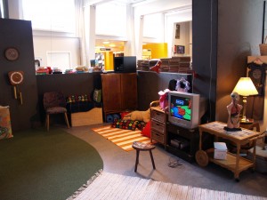 Et hjørne af pulterkammeret fyldt med gamle møbler, tæpper, puder og en Nintendo NES.
